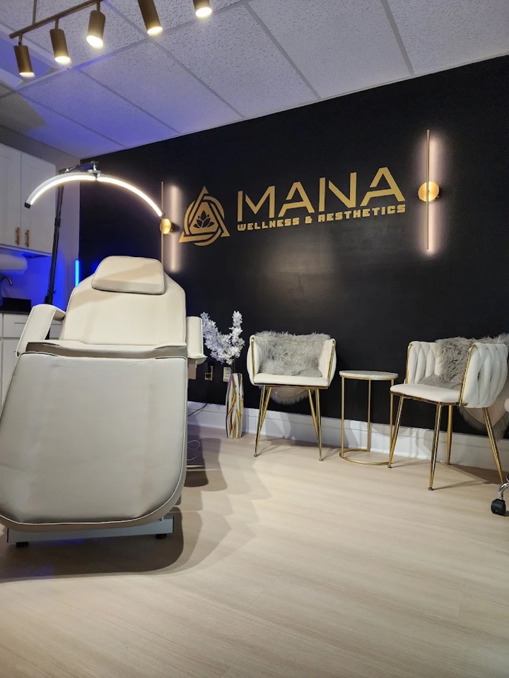 A treatment room at the Denville practice, with a treatment chair, ring light and seating beneath the Mana wall sign