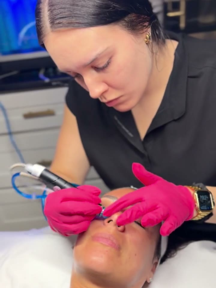 A clinician leaning in, concentrating, treating the skin around a patient's eye
